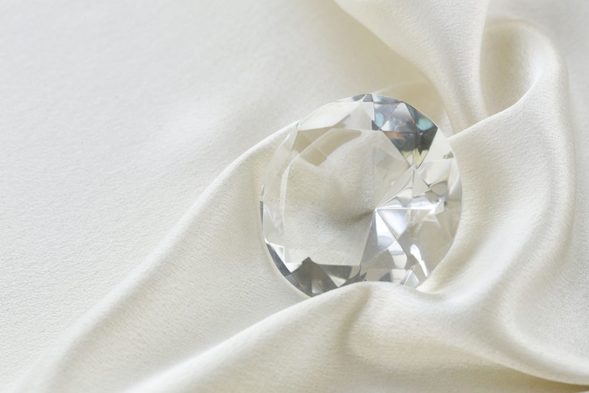 gros plan sur un diamant taillé et posé sur un tissu clair