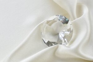 gros plan sur un diamant taillé et posé sur un tissu clair