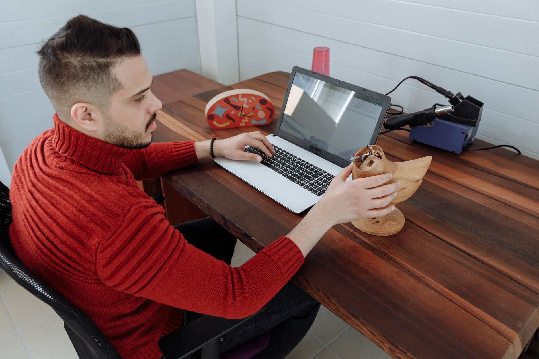 Un homme assis devant un ordinateur portable sur un bureau en bois.