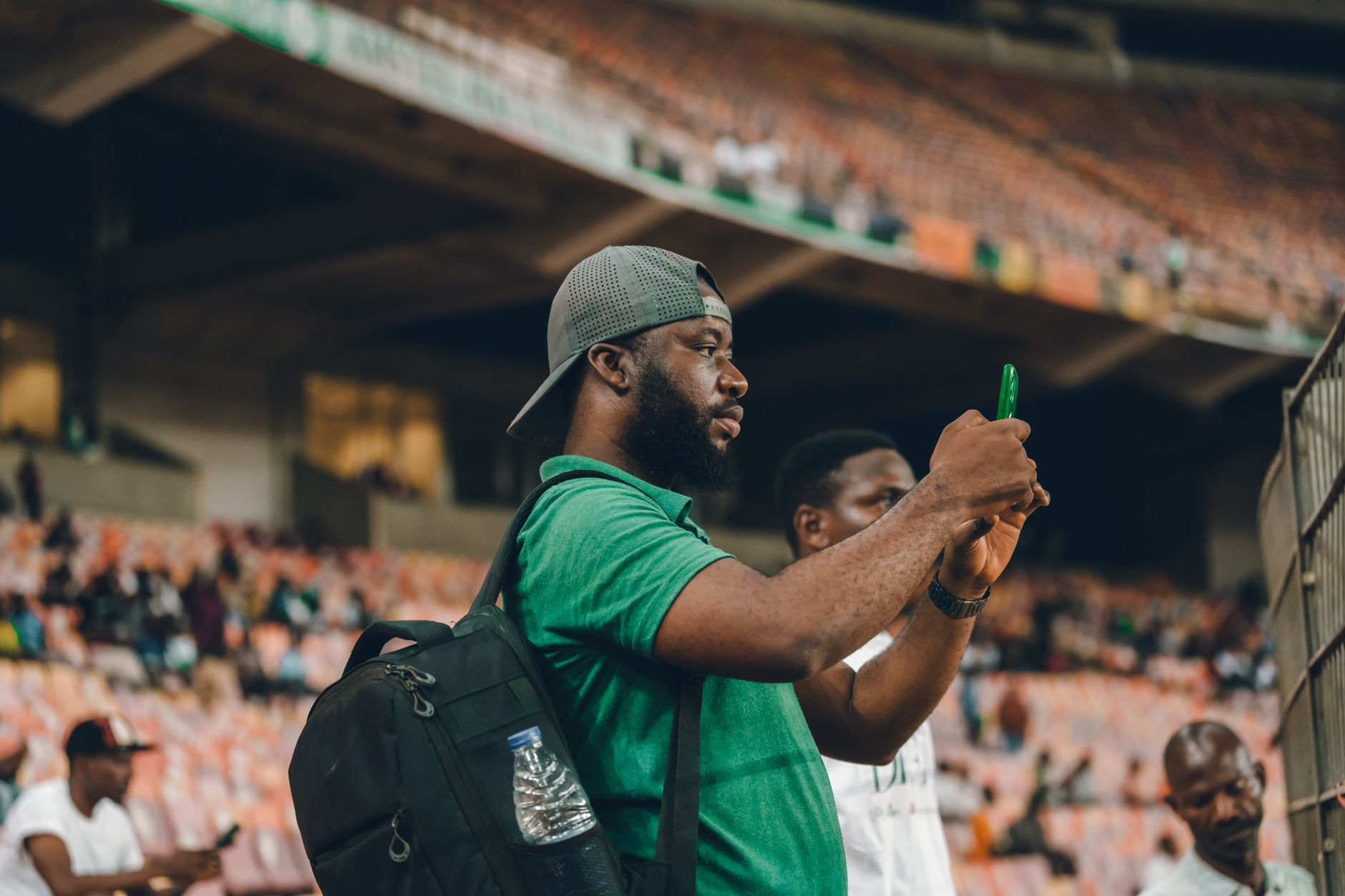Un homme consulte son smartphone dans les tribunes d'un stade.
